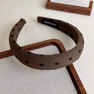 Gros plan du serre-tête artisanal en tissu marron café avec broderie florale fine