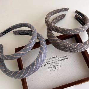Detailed view of handmade striped headbands with gold metallic thread and logo labels