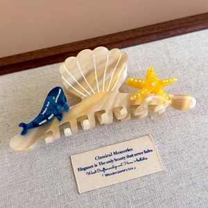 Detailed view of large shell-shaped hair claw with cute whale and starfish details