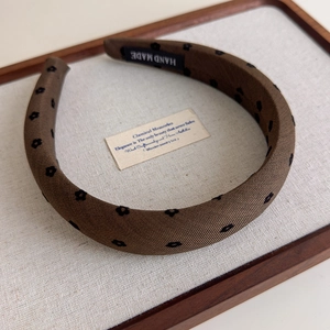 Détail du serre-tête floral marron avec étiquette fait main sur un présentoir élégant