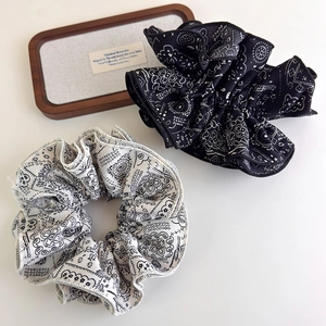 Detailed view of black and white paisley print fabric scrunchies with neat stitching