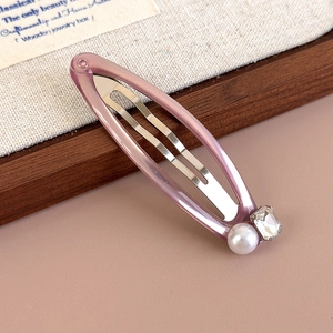 Close-up of a purple translucent hair clip featuring a round pearl and a square crystal