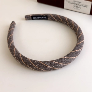Close-up of grey linen headband with orange stripes and handmade label detail