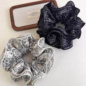 Macro detail of high-quality paisley print scrunchies in elegant black and white silk fabric