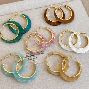 Macro shot of colorful C-shaped acetate hoop earrings with metallic gold inner rings