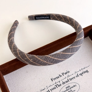 Close-up of dark grey striped linen headband featuring a black handmade textile label