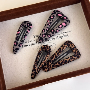 Set of leopard print fabric hair clips in brown and pink grey on vintage display