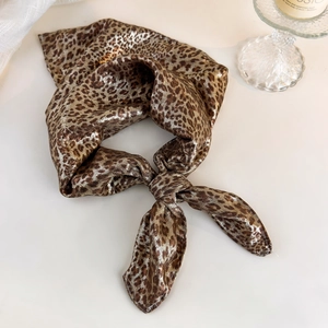 Detail of silk satin leopard print headscarf with knot design on white tabletop