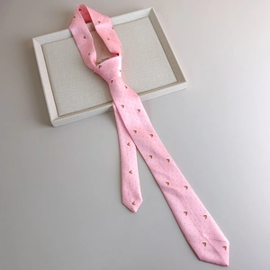 Detail of pink striped tie with golden bear patterns on a textured display tray