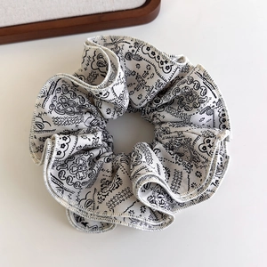 Close-up of oversized black and white paisley print fabric scrunchie with soft pleats