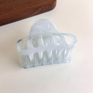 Detail showing marble texture and metal spring on translucent cloud-shaped hair claw clip