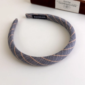 Detailed close-up of handmade striped fabric headband featuring a black woven brand label