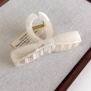 Detail of cream white acetate hair claw with star and cloud shape and gold spring