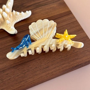 Detailed view of acetate shark hair clip with shell, whale, and starfish ornaments