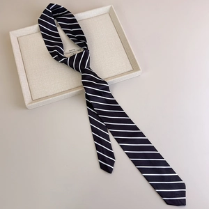 Macro view of black striped tie with fine white lines on a beige display tray