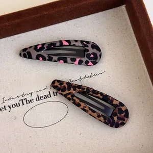 Close-up of leopard print hair clips in brown and pink fabric over metal BB clips