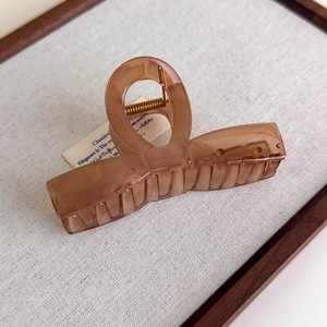 Detail view of a large translucent amber brown hair claw clip with cross-loop design