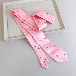 Detail of pink silk tie with red polka dots and cute animal patterns on a grey tray