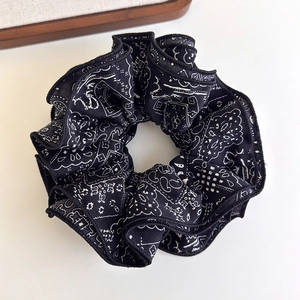 Detailed view of paisley pattern on black and white fabric scrunchie with soft folds