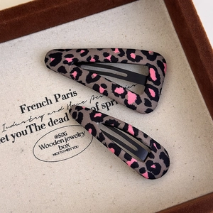 Close-up of pink leopard print hair clips in triangle and teardrop shapes on wood box