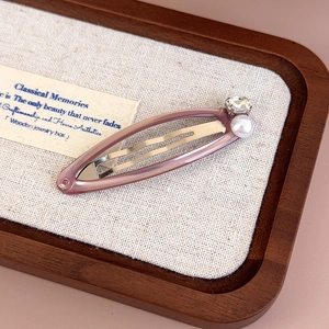 Detail of elegant hair clip with purple resin, faux pearl and rhinestone on a linen tray