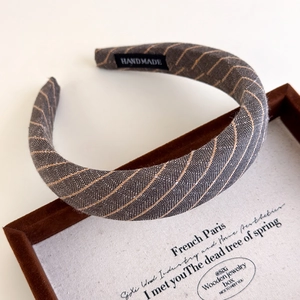 Macro detail of dark gray striped fabric headband showing the handmade inner label quality
