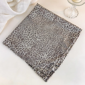 Macro shot of silk leopard print square scarf with leopard pattern on textured white background