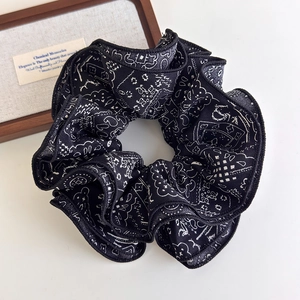 Detailed close-up of a vintage black paisley scrunchie with white floral patterns