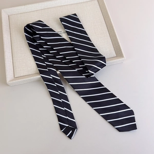 Close-up of elegant black and white striped silk necktie on a minimalist beige background