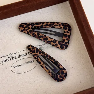Detailed view of two leopard print fabric hair clips on a velvet display box