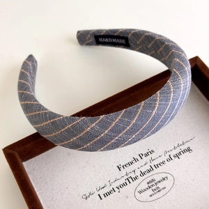 Close-up of handmade blue striped fabric headband on a luxury wooden display box