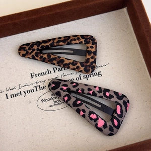 Detail view of triangular leopard print hair clips on a vintage fabric tray