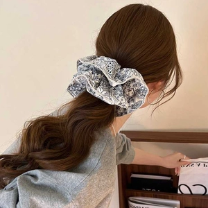 Blue paisley print large fabric scrunchie shown in a stylish side view on hair