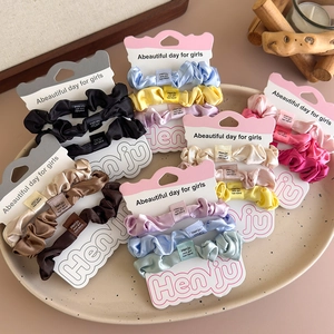 Set of 3 colorful satin scrunchies displayed on display cards in a ceramic tray