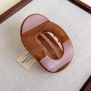 Macro shot of large amber resin hair claw clip with smooth glossy finish and cutout design