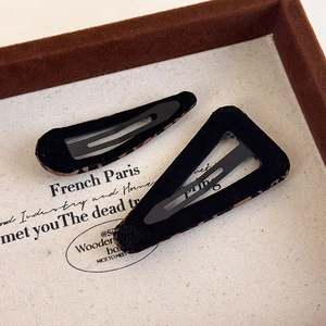 Detail of leopard print fabric hair clips in teardrop and triangle shapes on a vintage tray