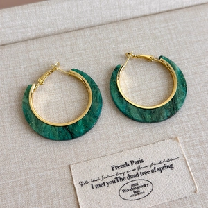 Detailed close-up of C-shaped emerald marble resin earrings with gold glitter accents