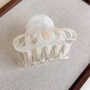 Detail of large hair claw clip in white marble acetate finish with interlocking teeth