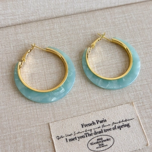 Detail of C-shaped green marble resin earrings with gold-toned metal inner ring