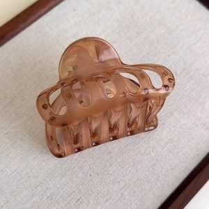 Macro detail of the amber resin hair claw clip with multi-tooth grip and polished finish