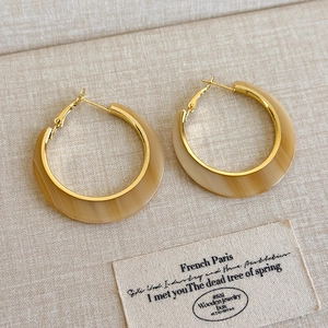 Detail of C-shaped resin earrings with marble texture and golden metal base