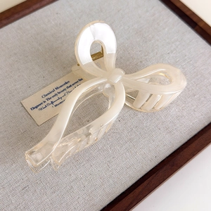 Macro detail of a pearlescent cream hair claw clip with a durable gold metal spring