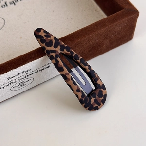 Close-up of leopard print fabric water drop hair clip on vintage velvet display
