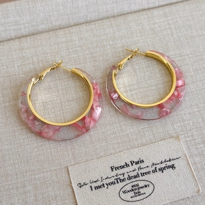 Detail of pink marble resin C-shaped hoop earrings with gold metal accents on display