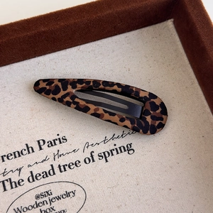 Macro detail of leopard print fabric BB hair clip with textured brown and black pattern