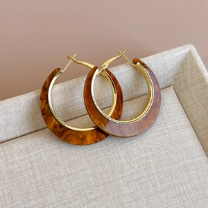 Close-up of vintage C-shaped hoop earrings with gold metal frame and tortoiseshell resin