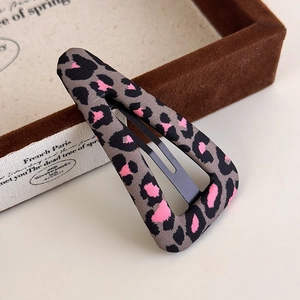 Detail of triangular leopard print hair clip with pink accents on a velvet jewelry box