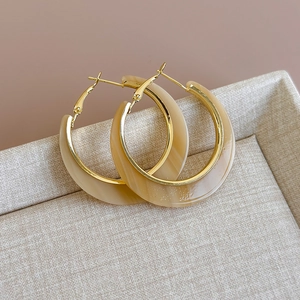 Detailed close-up of C-shaped marble resin earrings with elegant golden metal frames