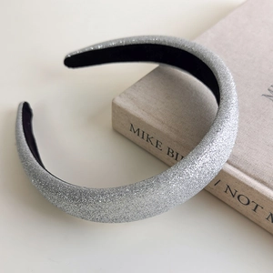 Detail of silver glitter sponge headband with shimmering sequins on textured book