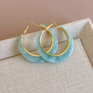 Detailed macro view of mint green marble resin C-hoop earrings with gold metal frame